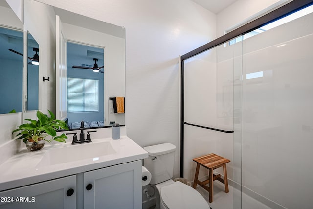 bathroom with ceiling fan, vanity, a shower with shower door, and toilet