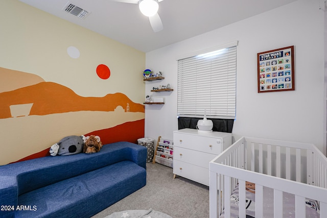 bedroom featuring ceiling fan, light colored carpet, and a crib