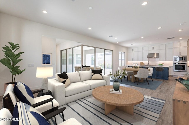 living area with recessed lighting, visible vents, and light wood-type flooring