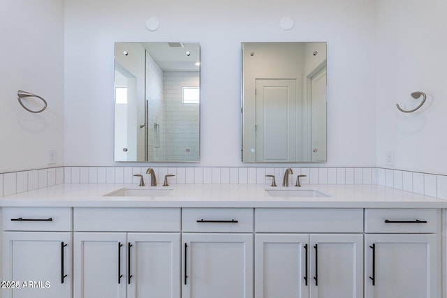 bathroom with double vanity, a stall shower, and a sink