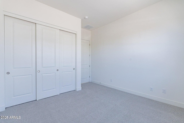 unfurnished bedroom featuring a closet, visible vents, light colored carpet, and baseboards