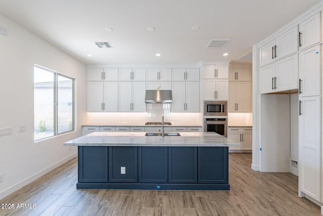 kitchen with under cabinet range hood, visible vents, appliances with stainless steel finishes, and white cabinetry