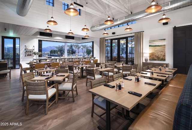 dining space with visible vents, a barn door, french doors, a high ceiling, and wood finished floors