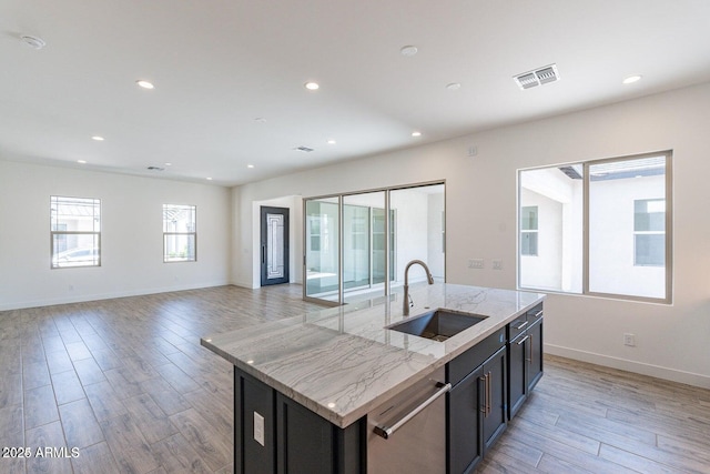 kitchen featuring visible vents, light wood finished floors, an island with sink, a sink, and dishwasher