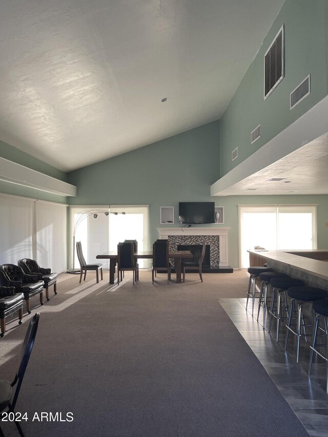 interior space with high vaulted ceiling, a fireplace, and carpet floors