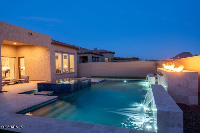 pool at dusk with a patio, an in ground hot tub, and pool water feature