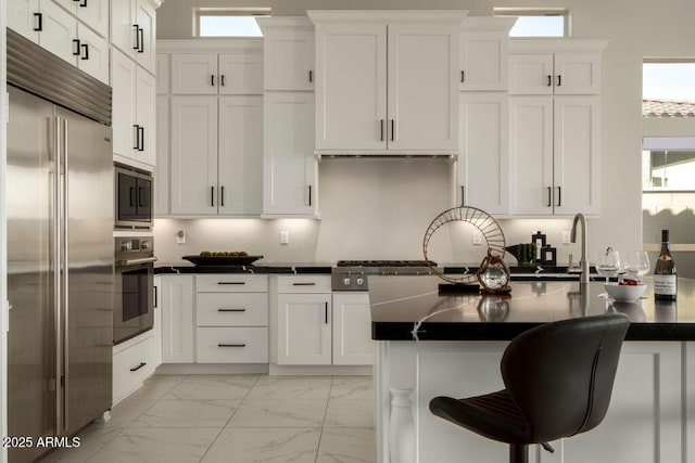 kitchen featuring white cabinetry, sink, and built in appliances