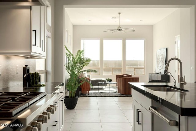 kitchen with white cabinetry, sink, stainless steel counters, and tasteful backsplash