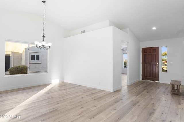 interior space with a notable chandelier, light hardwood / wood-style floors, and lofted ceiling