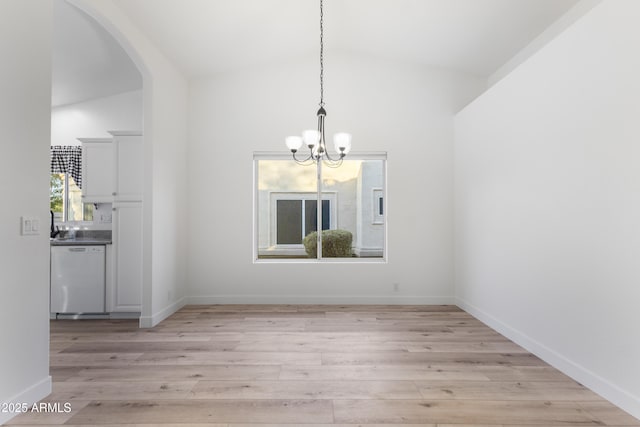 unfurnished dining area featuring a chandelier, high vaulted ceiling, and light hardwood / wood-style flooring