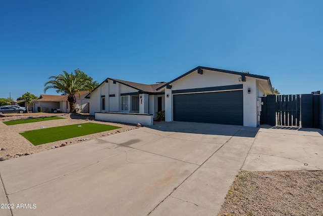 view of front of home featuring stucco siding, driveway, an attached garage, and a gate