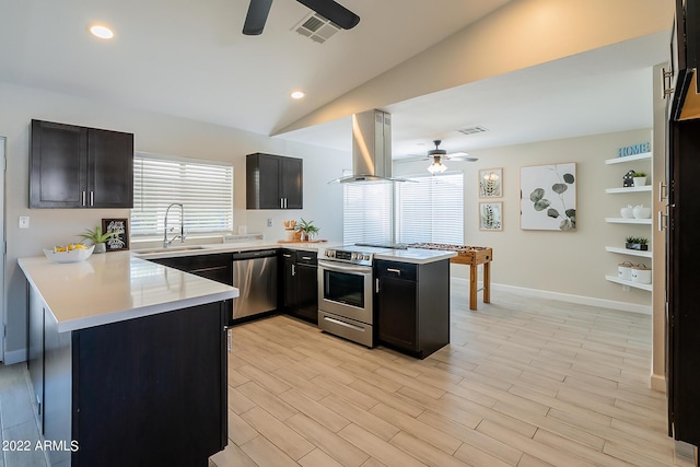 kitchen with appliances with stainless steel finishes, a peninsula, ceiling fan, and island range hood