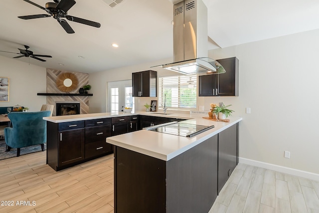 kitchen with light countertops, a peninsula, island exhaust hood, black electric cooktop, and a sink