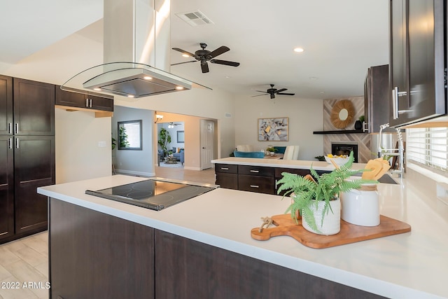 kitchen featuring visible vents, light countertops, dark brown cabinetry, black electric cooktop, and island range hood