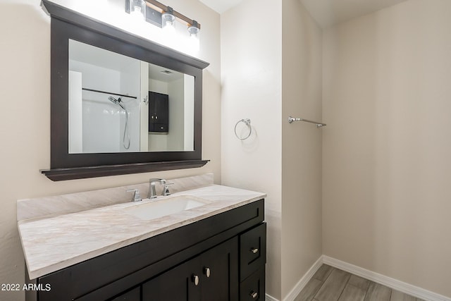 bathroom with vanity, wood finished floors, and baseboards