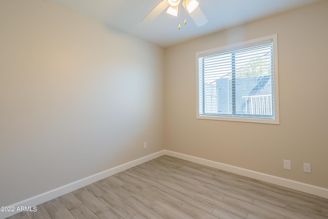 spare room with baseboards, light wood finished floors, and ceiling fan