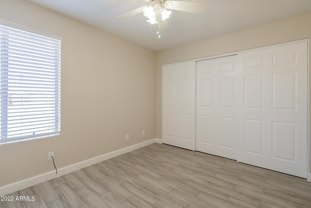 unfurnished bedroom featuring light wood finished floors, a ceiling fan, baseboards, and a closet