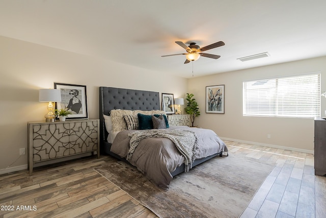 bedroom featuring visible vents, ceiling fan, baseboards, and wood finished floors