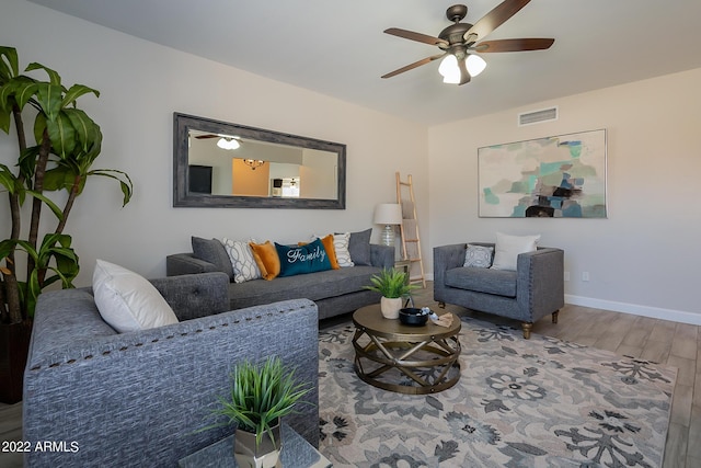 living area featuring a ceiling fan, wood finished floors, visible vents, and baseboards