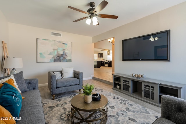 living area with visible vents, baseboards, ceiling fan, and light wood-style flooring