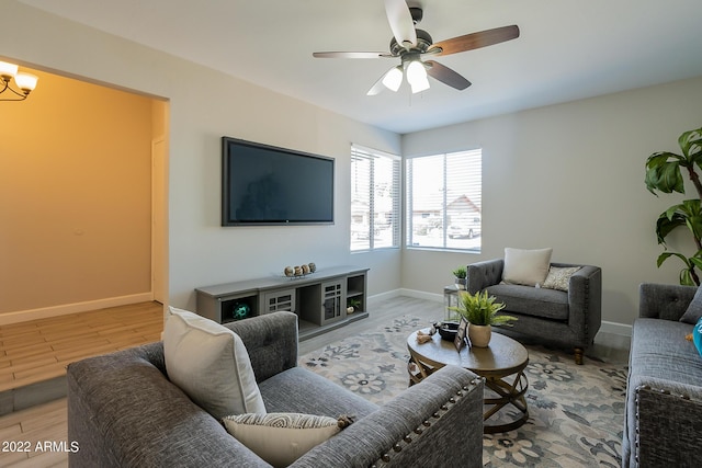 living room with ceiling fan with notable chandelier, wood finished floors, and baseboards