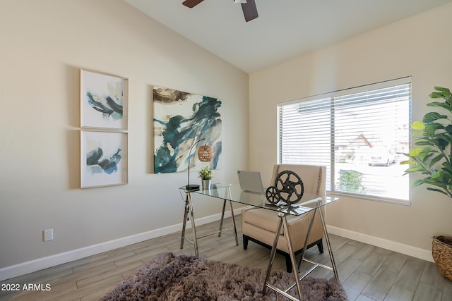 office space with baseboards, light wood-style floors, a ceiling fan, and vaulted ceiling