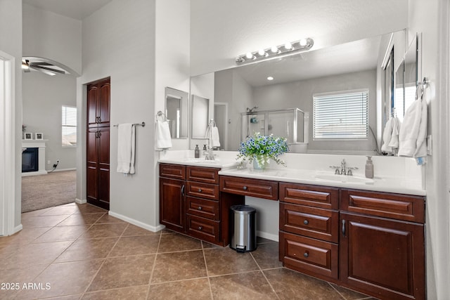 4418 W Yoosooni Dr, New River, AZ 85087 - bathroom with double vanity, a shower stall, a ceiling fan, tile patterned floors, and a glass covered fireplace