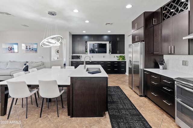 4418 W Yoosooni Dr, New River, AZ 85087 - kitchen featuring stainless steel appliances, backsplash, light countertops, a kitchen island with sink, and a kitchen breakfast bar