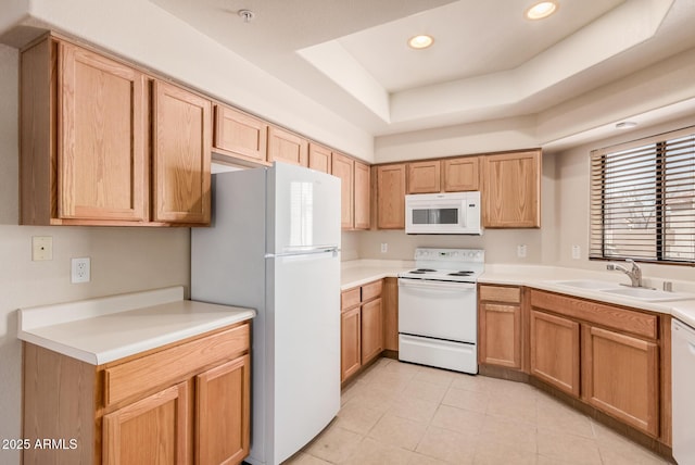 kitchen featuring a tray ceiling, sink, and white appliances