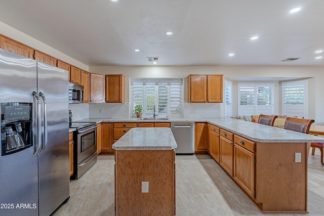 kitchen with appliances with stainless steel finishes, kitchen peninsula, decorative backsplash, a kitchen island, and sink