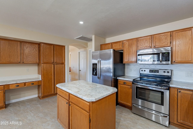 kitchen with appliances with stainless steel finishes, decorative backsplash, and a center island