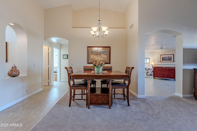 carpeted dining room with high vaulted ceiling and ceiling fan with notable chandelier