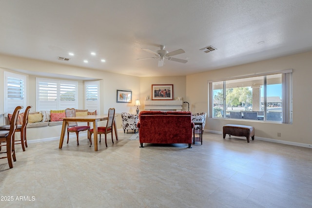 living room with a textured ceiling, ceiling fan, and a healthy amount of sunlight