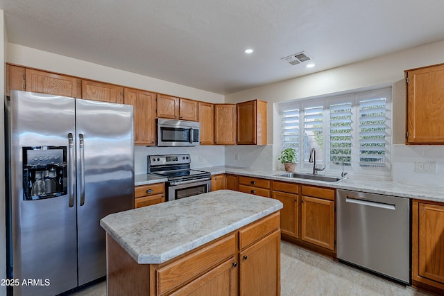 kitchen featuring stainless steel appliances, sink, a center island, backsplash, and light stone countertops