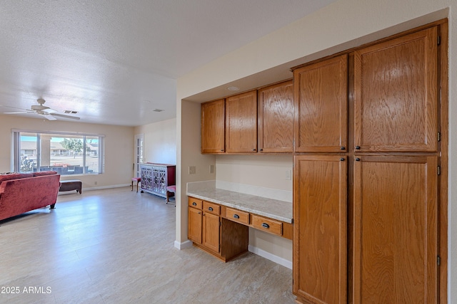 kitchen with light wood-type flooring, ceiling fan, and built in desk