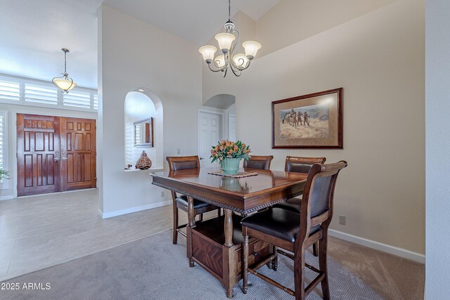 carpeted dining room featuring a high ceiling and an inviting chandelier