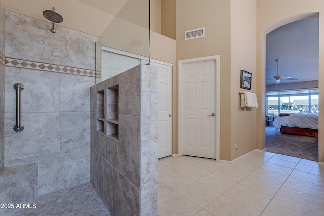 bathroom with ceiling fan, tiled shower, tile patterned flooring, and a towering ceiling