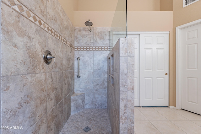 bathroom with tiled shower and tile patterned flooring