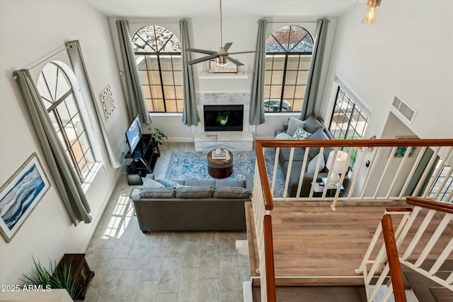 living room with a ceiling fan, a towering ceiling, stairway, and a high end fireplace