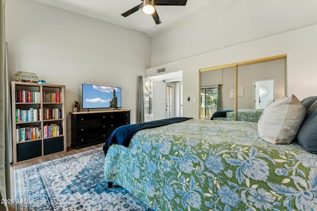 bedroom with a closet, ceiling fan, high vaulted ceiling, and wood finished floors