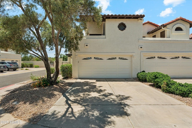 view of front of property featuring an attached garage, a tiled roof, driveway, stucco siding, and fence