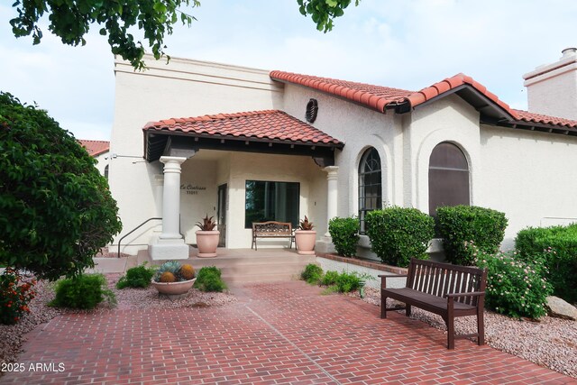 back of property featuring stucco siding, a tiled roof, and a porch
