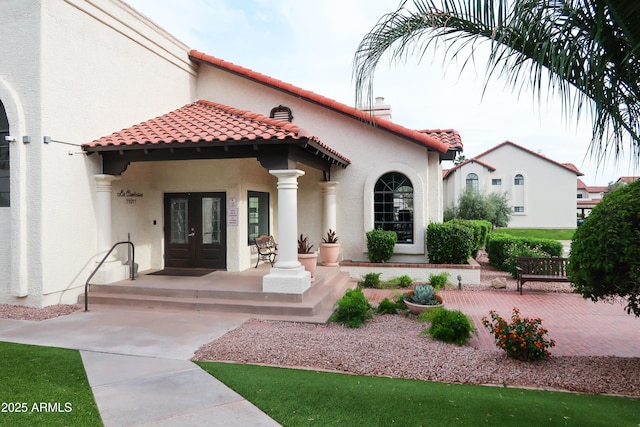 view of front facade featuring french doors, a tile roof, and stucco siding