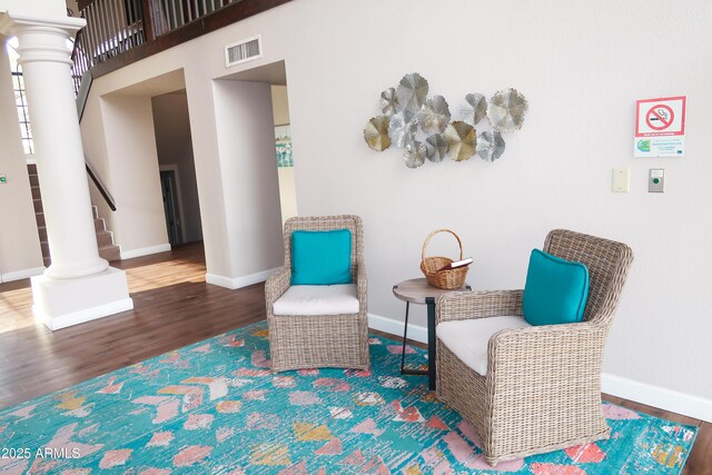living area with wood finished floors, decorative columns, stairway, and baseboards