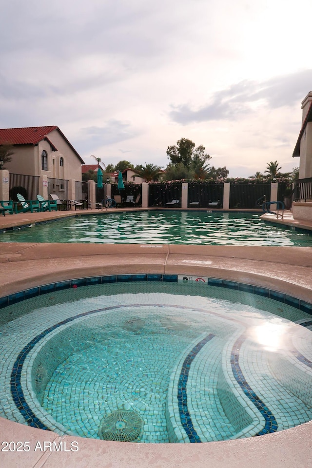 view of pool featuring fence and a community hot tub