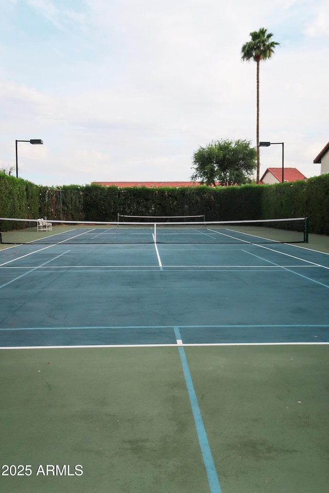 view of tennis court with community basketball court and fence