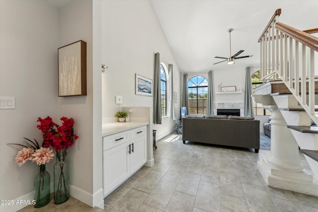 living room with a ceiling fan, stairway, lofted ceiling, a fireplace, and baseboards