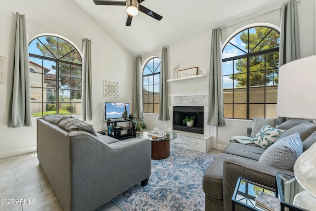 living room with ceiling fan, baseboards, a high end fireplace, and high vaulted ceiling
