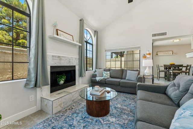 living room with baseboards, a fireplace, and high vaulted ceiling