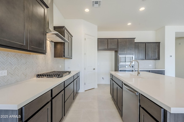 kitchen with a kitchen island with sink, sink, wall chimney range hood, and stainless steel appliances